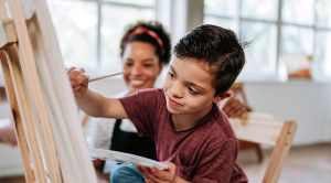 Teacher assisting a child with Down syndrome - painting class on canvas 